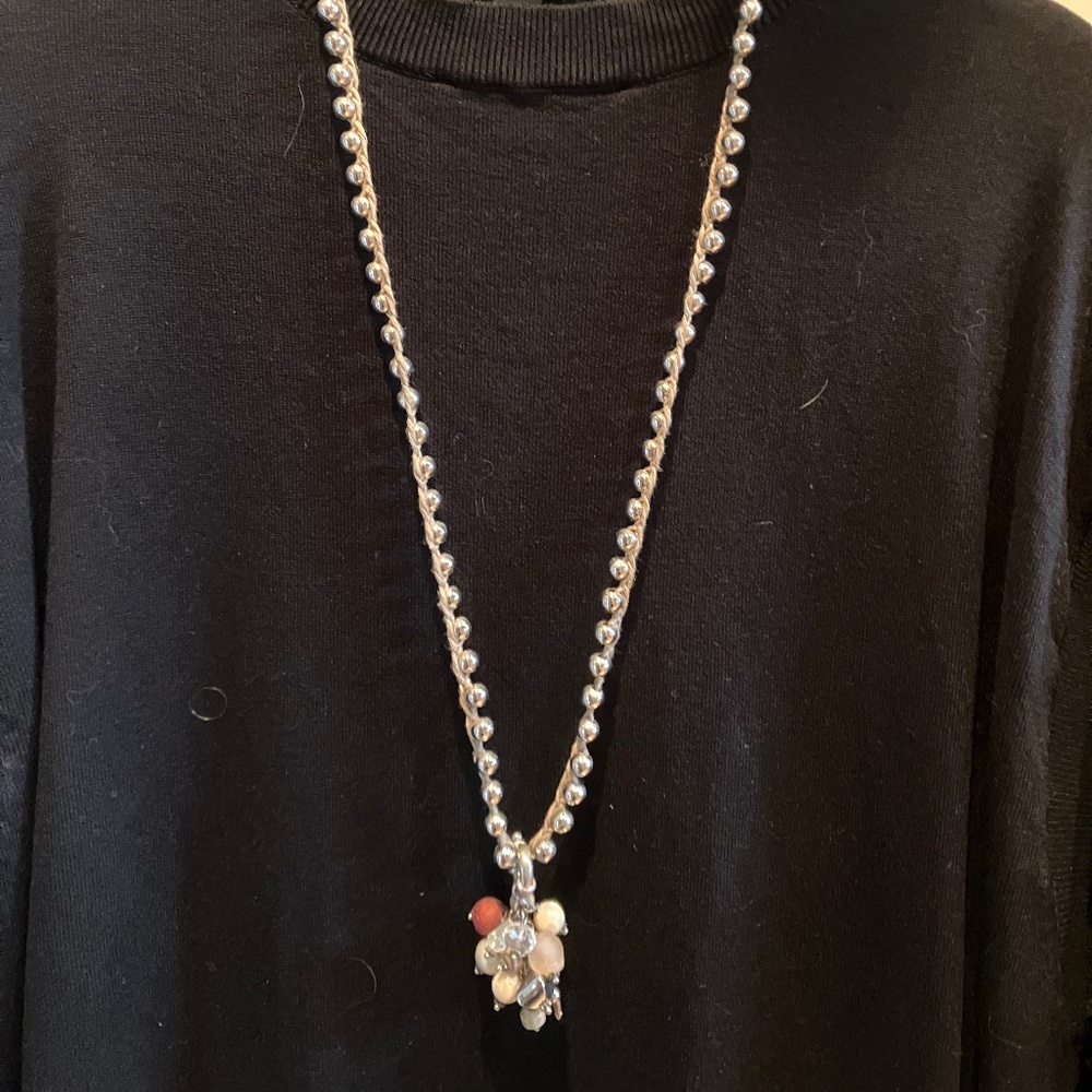Silver beaded necklace on rafia cord with decorative medallion